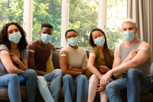 Group of happy diverse female and male friends in face masks sho