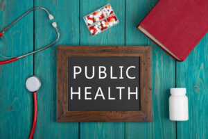 Blackboard with text “Public health”, pills, book and stethoscope on wooden background