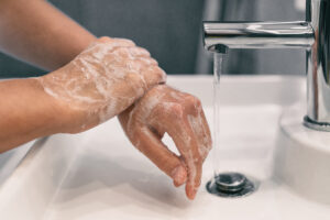 Hand washing personal hygiene woman washing hands rubbing soap for 20 seconds following steps, cleaning wrists and rinsing under water at home bathroom. COVID-19 infection prevention handwashing.