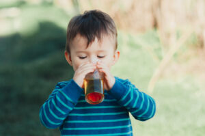 charming boy in nature drinking Apple juice