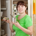 woman putting with metal can near fridge