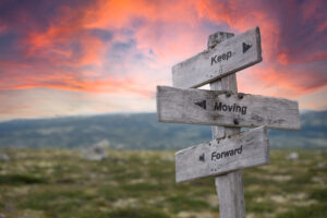 keep moving forward text engraved in wooden signpost outdoors in