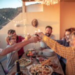 Group of friends celebrating toasting with drinks the new year. Male and female friends make toast Aas they celebrate at party. Group of people with teen laughing out loud outdoor with glasses in hand